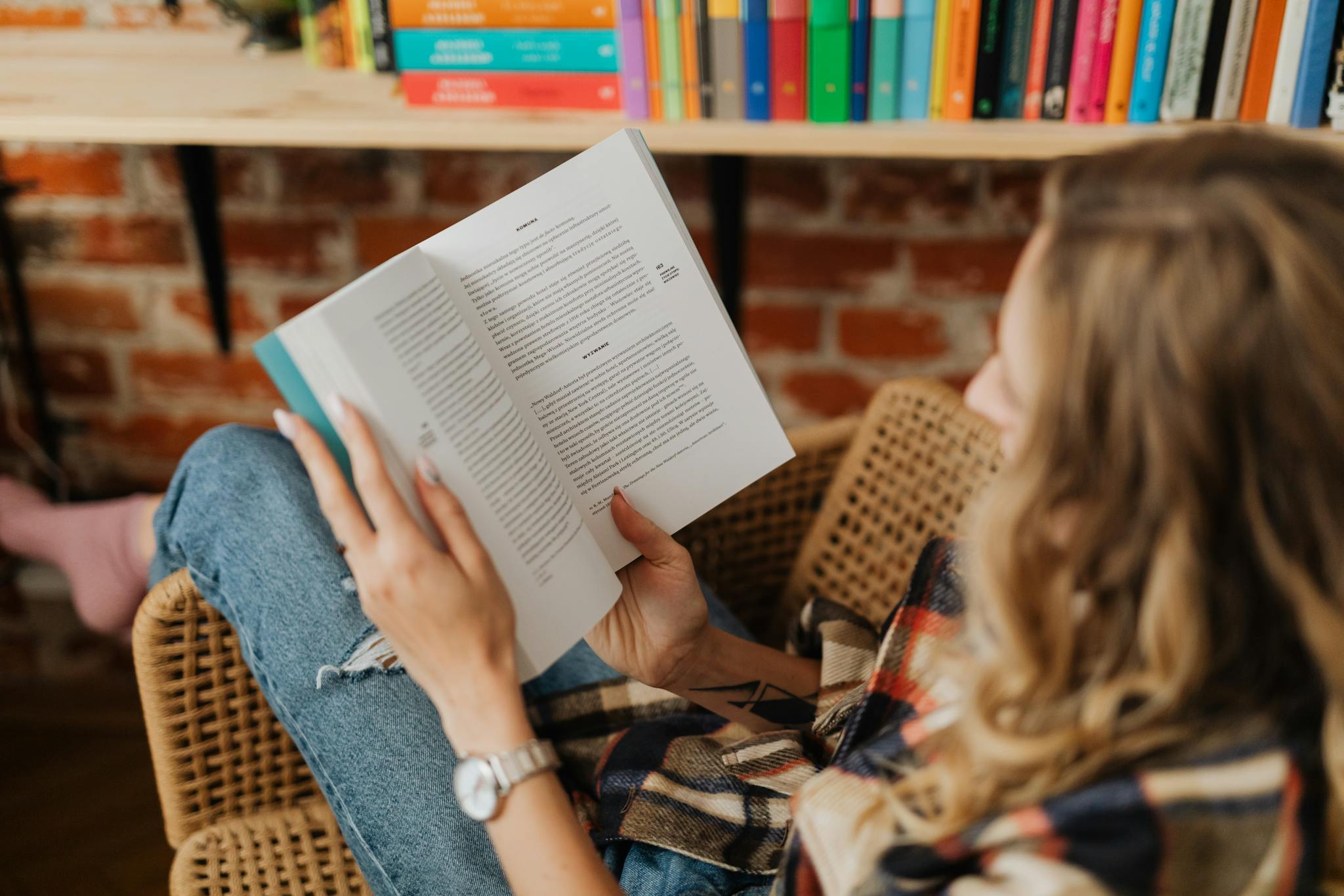 A woman sitting comfortably indoors enjoying her book in a cozy and peaceful setting.